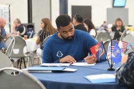 A veteran sits a table filling out his information for assistance.